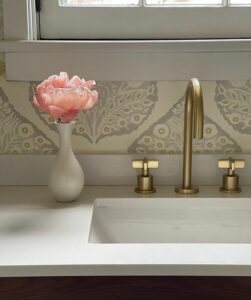 Featured image showing a romantic modern bathroom with a peony in a vase next to an undermount sink and brass Watermark Designs faucet.