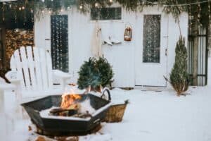Featured image showing a front porch of rustic country house in winter in snow with fire bowl, suburban area with stylish decor