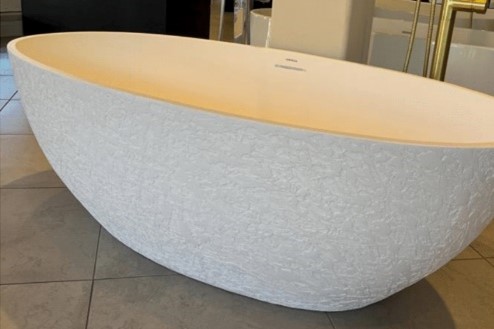 Inline image showing a textured freestanding bathtub by Americh on a showroom floor.